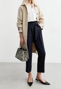 Trench coat beige, blusa blanca, pantalones de talle alto azul marino, bailarinas negras de punta, y un bolso de serpiente. Tejido suave y líneas limpias.