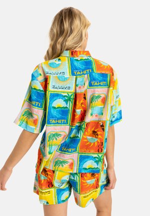 Chemise à manches courtes de couleurs vives avec un imprimé tropical présentant divers motifs de palmiers, de soleils et de scènes océaniques. Fabriquée en tissu léger.