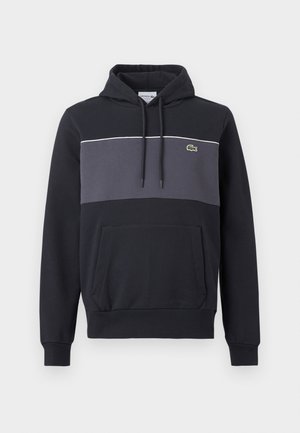 Μαύρο φούτερ με κουκούλα, με σκούρο γκρι πάνελ στο στήθος, ρυθμιζόμενο κορδόνι στην κουκούλα, εμπρόσθια τσέπη τύπου καγκουρό και μικρό πράσινο λογότυπο κροκοδείλου στο στήθος.