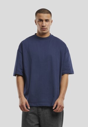 T-shirt oversize bleu marine en coton. Présente un col rond et des manches courtes, avec une texture douce et un design minimal.