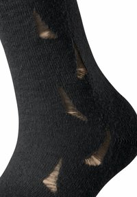 Schwarze Socken mit strategischen Ausschnitten, die den helleren Stoff darunter zeigen. Sie haben eine gerippte Textur und einen nahtlosen Abschluss an der Oberseite.