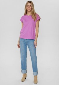 Korte mouwen, ronde hals t-shirt in levendig paars, gecombineerd met lichtblauwe hoge taille spijkerbroek met opgerolde mouwen en beige enkellaarsjes.