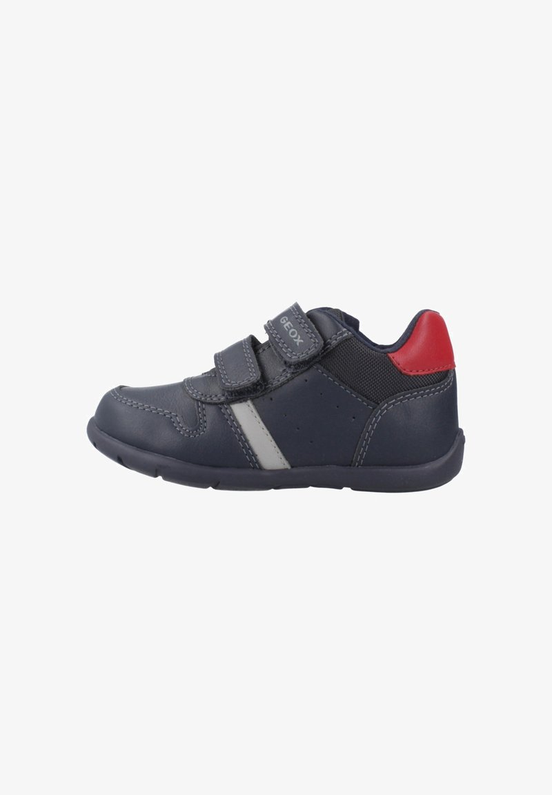 Zapatillas con tiras de velcro en piel azul marino con detalles grises, que cuentan con un talón rojo, puntera redondeada, cuello acolchado y suela de goma texturizada.
