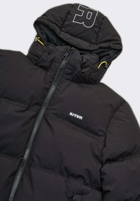 Giacca piumino nera con zip frontale, cappuccio regolabile con accenti gialli e un logo bianco prominente sul cappuccio e sull'area del petto.