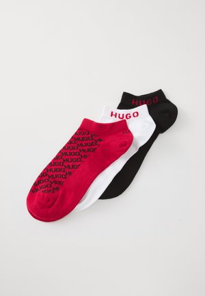Tre par lave sokker i rød, hvit og svart, alle med "HUGO"-merke; det røde paret har gjentatte svarte logoer.