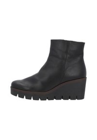 Botte en cuir noir à talon compensé. Présente une texture lisse, un bout arrondi et une semelle épaisse et crantée pour une meilleure adhérence.