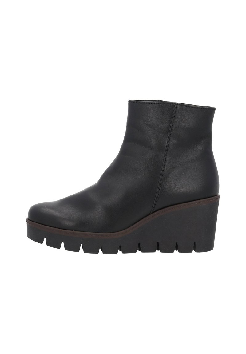 Botte en cuir noir à talon compensé. Présente une texture lisse, un bout arrondi et une semelle épaisse et crantée pour une meilleure adhérence.
