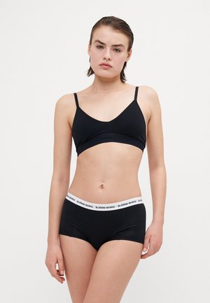 Reggiseno nero con spalline regolabili e fascia con logo. Pantaloni corti neri a vita alta con waistband bianco con logo. Tessuto liscio e elasticizzato, design minimalista.