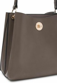 Sac à main en cuir gris avec un design structuré, présentant un accent en métal doré de forme circulaire et une texture lisse. Comprend une bandoulière.
