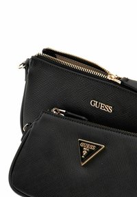 Borsa a tracolla nera in sintetico con superficie texture, due scomparti con zip, dettagli in metallo dorato e un accento a logo triangolare.