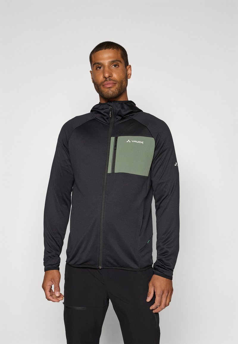 Schwarze Zip-Jacke mit einer grünen Brusttasche, ausgestattet mit einer Kapuze und langen Ärmeln, aus leichtem, glatt-texturiertem Stoff gefertigt.