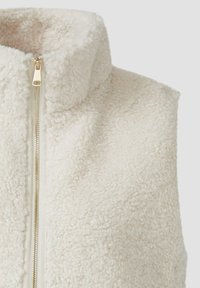 Cremefarbener Fleece-Westen mit hohem Kragen, durchgehendem Reißverschluss und weicher, strukturierter Oberfläche; ausgestattet mit goldfarbener Reißverschlussbeschläge.