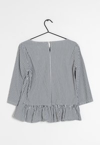 Svart och vit randig blus med trekvartslånga ärmar, peplum-öppning och nyckelhålsöppning bak. Lättviktig tyg med slät textur.
