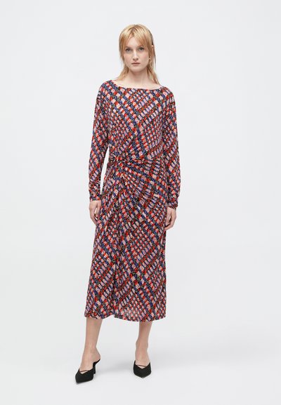 Vestido midi de mangas longas com um padrão geométrico em vermelho, azul e branco, apresentando um detalhe de cintura drapeada e um decote largo.