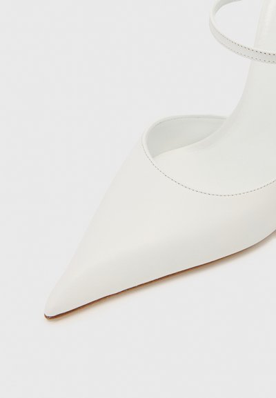 Bílé kožené lodičky s špičatou špičkou a hladkým povrchem, s otevřenými stranami a tenkým páskem kolem kotníku. Podešev je v kontrastní hnědé barvě.