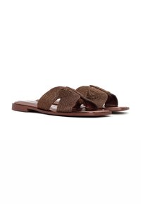 Sandales à glissière tressées marron avec deux larges brides, une semelle plate et une finition lisse. Texture notable provenant du design tressé.