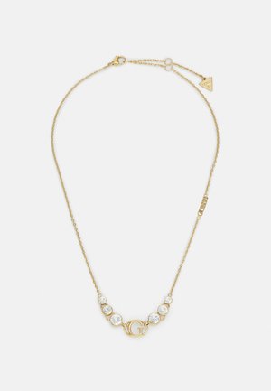 Collier fin en chaîne d’or avec un pendentif central "G" et six pierres précieuses rondes et claires, trois de chaque côté du pendentif.