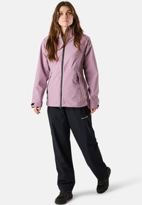 Light pink waterproof jacket with a full zipper, side pockets, black accents; paired with black waterproof pants and dark footwear.