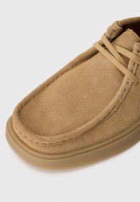 Pantof brown din suede, cu vârf rotunjit, design cu șireturi și o suprafață texturată; dispune de un toc gros, din cauciuc transparent.
