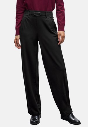 Pantalones anchos negros de tela suave, con cintura ceñida y hebilla rectangular, bolsillos laterales y un corte relajado.
