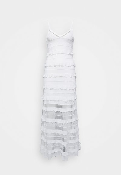 Hvit ermeløs kjole med V-hals, som har et lagdelt design med volangstoff og åpne strikkede sektioner. Lengden går til midt på leggen.