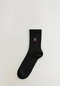 Svart bomullssocka med en broderad design av lila druvklasar. Socken har en enhetlig färg och en sömlös tå.