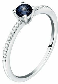 Saphirring mit einem zentralen dunkelblauen Edelstein, silbernem Band und kleineren Diamanten an einer Seite, mit einer polierten Oberfläche und zartem Design.