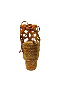 Sandalo con tacco in pelle marrone, caratterizzato da un design con ritagli, lacci annodati e un tacco in juta intrecciata, che mette in risalto una texture naturale e una certa altezza.