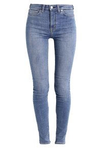 Jeans skinny de mezclilla azul con una cintura alta, que presentan un diseño estándar de cinco bolsillos y detalles de costura mínimos, textura suave y un lavado medio.