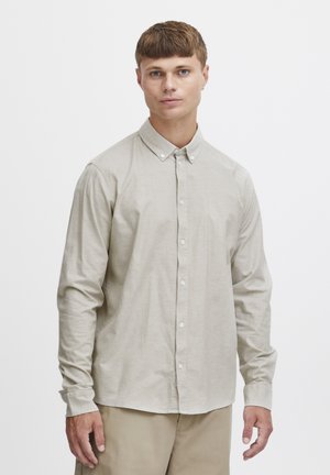 Lyse beige knapp-up skjorte laget av glatt stoff, med klassisk krage, lange ermer og rett nederkant med en subtil tekstur.