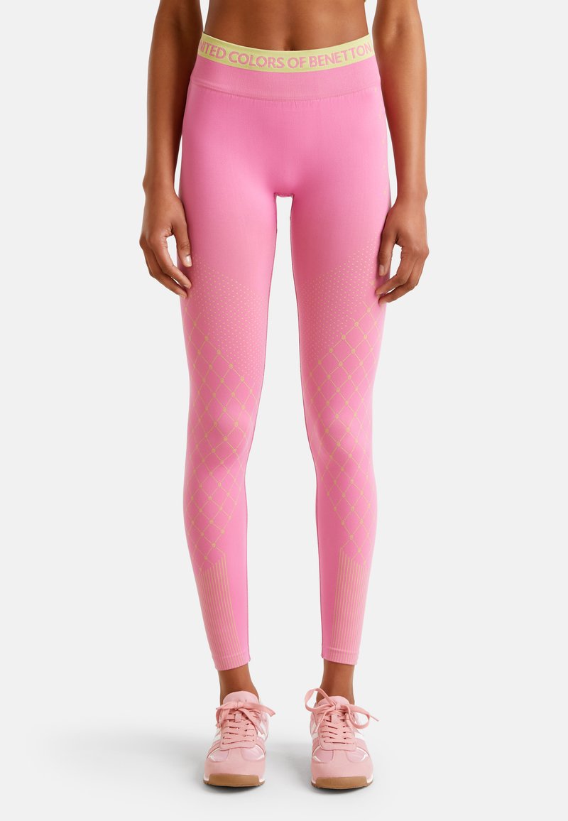 Leggings roses avec une large ceinture jaune, ornées de motifs en diamant et de pois, fabriquées en tissu doux, conçues pour les activités sportives.