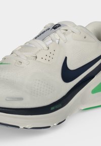 Λευκό αθλητικό παπούτσι Nike React με σκούρο μπλε λογότυπο, πράσινες λεπτομέρειες και λευκά κορδόνια, από πλευρική και εμπρόσθια γωνία.