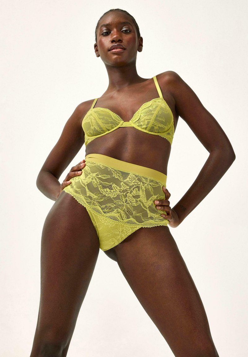 Bralette in pizzo verde lime con sottocoppa e coordinato slip alto in vita. Motivo floreale, texture morbida e dettagli decorativi.