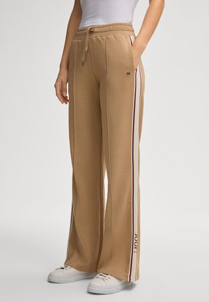 Beige, brede sweatpants met een trekkoord in de taille, zijzakken en twee verticale strepen in bordeaux en wit. Merklogo op de bovenbeen.