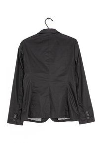 Blazer negro a medida colgado de una percha negra, visto desde la parte posterior, con mangas largas y puños abotonados.