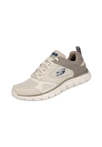 Zapatilla deportiva Skechers en beige claro con superposiciones de malla y sintético. Presenta punta redondeada, cordones planos, suela acolchada y un logotipo distintivo.