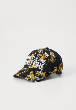 Černá kšiltovka s propracovanými zlatými a bílými barokními vzory, s logem "VERSACE JEANS COUTURE" výrazně umístěným v přední části.