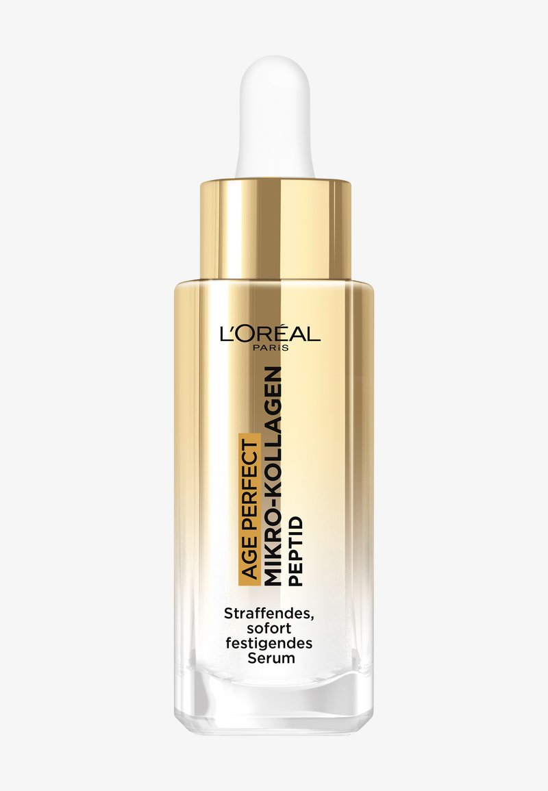 Transparant glazen druppelflesje met een gouden hals en dop, gevuld met een doorschijnend serum. Voorzien van merk- en producttekst in zwart en goud.