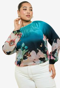 Blusa floreale in gradiente blu e nero con maniche lunghe e trasparenti, decorate con fiori rosa e farfalle. Scollatura arricciata e polsini elasticizzati.