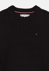 Pulover negru tricotat, cu un model de cablu, guler rotund și un accent subtil al logo-ului Tommy Hilfiger în culorile roșu, alb și albastru.