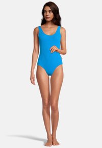 Maillot de bain une pièce bleu en ribbed avec un décolleté arrondi et des bretelles larges ; silhouette ajustée ; texture lisse et design minimal.