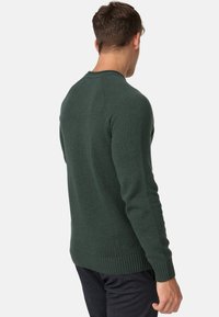 Pull en tricot vert avec un col rond, des poignets et un ourlet côtelés, présentant une finition texturée et une silhouette ajustée, vu de dos.