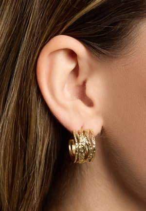 Boucles d'oreilles créoles en or avec un design texturé et superposé. Chaque créole présente une finition unique, combinant des éléments lisses et martelés.