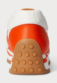 Balti ir oranžiniai odiniai sportbačiai su tekstūruotu guminio pado, su paminkštintu kulnu ir išraižytu logotipu gale.