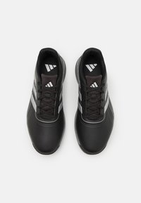 Zapatillas deportivas negras con una superficie texturizada, que cuentan con tres franjas plateadas y una lengüeta acolchada. Los cordones son negros, con una plantilla negra.