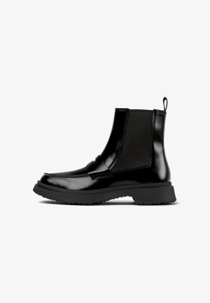Bottes noires brillantes à la cheville avec des panneaux élastiques sur les côtés et une semelle épaisse, dotées d'une languette pour un enfilage facile. Présentées sur un fond blanc.