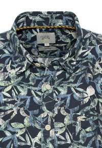 Korte mouwen overhemd in een marineblauwe linnenmix. Heeft een groen-blauw loofpatroon, een button-down kraag en beige knopen.