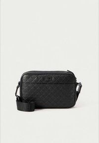 Černá texturovaná kabelka přes rameno se zipovým uzávěrem, diamantovým vzorem, odnímatelným popruhem a jemnou logovou nášivkou na přední straně.