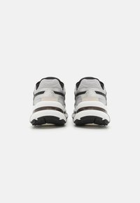 Baskets de sport avec un upper en mesh gris, des accents noirs et une semelle intermédiaire blanche épaisse. Caractérisées par une semelle extérieure texturée pour une meilleure adhérence.