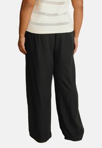 Svarta vida byxor i lätt tyg, med en slät yta och avslappnad passform, med en fåll som vilar ovanför golvet.